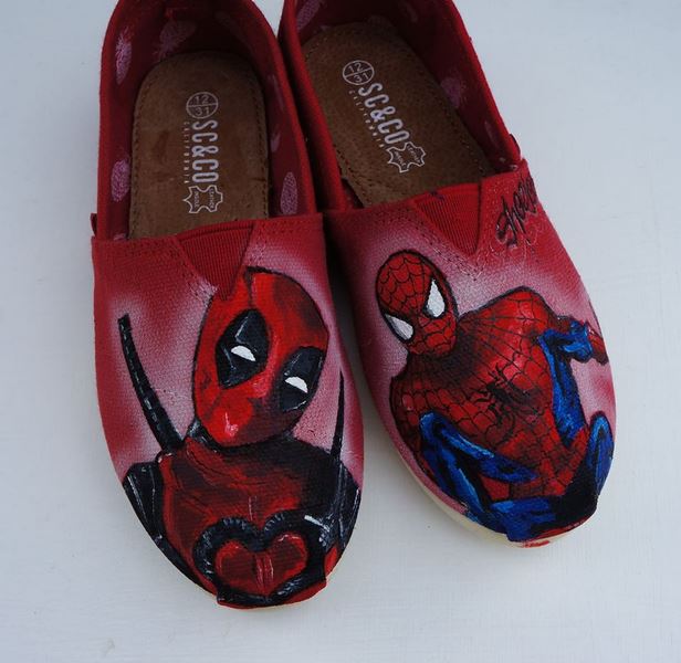 pair or red toms with deadpool and spiderman painted on them in realisitc style