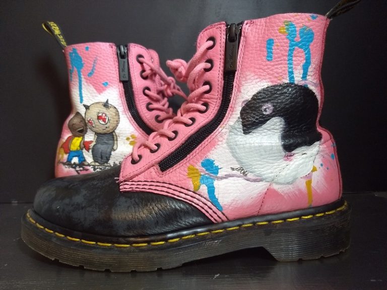 pink dr martens with a yin yang rat portrait on one foor and a graffiti style mother and shild on the other. the toes have been painted black